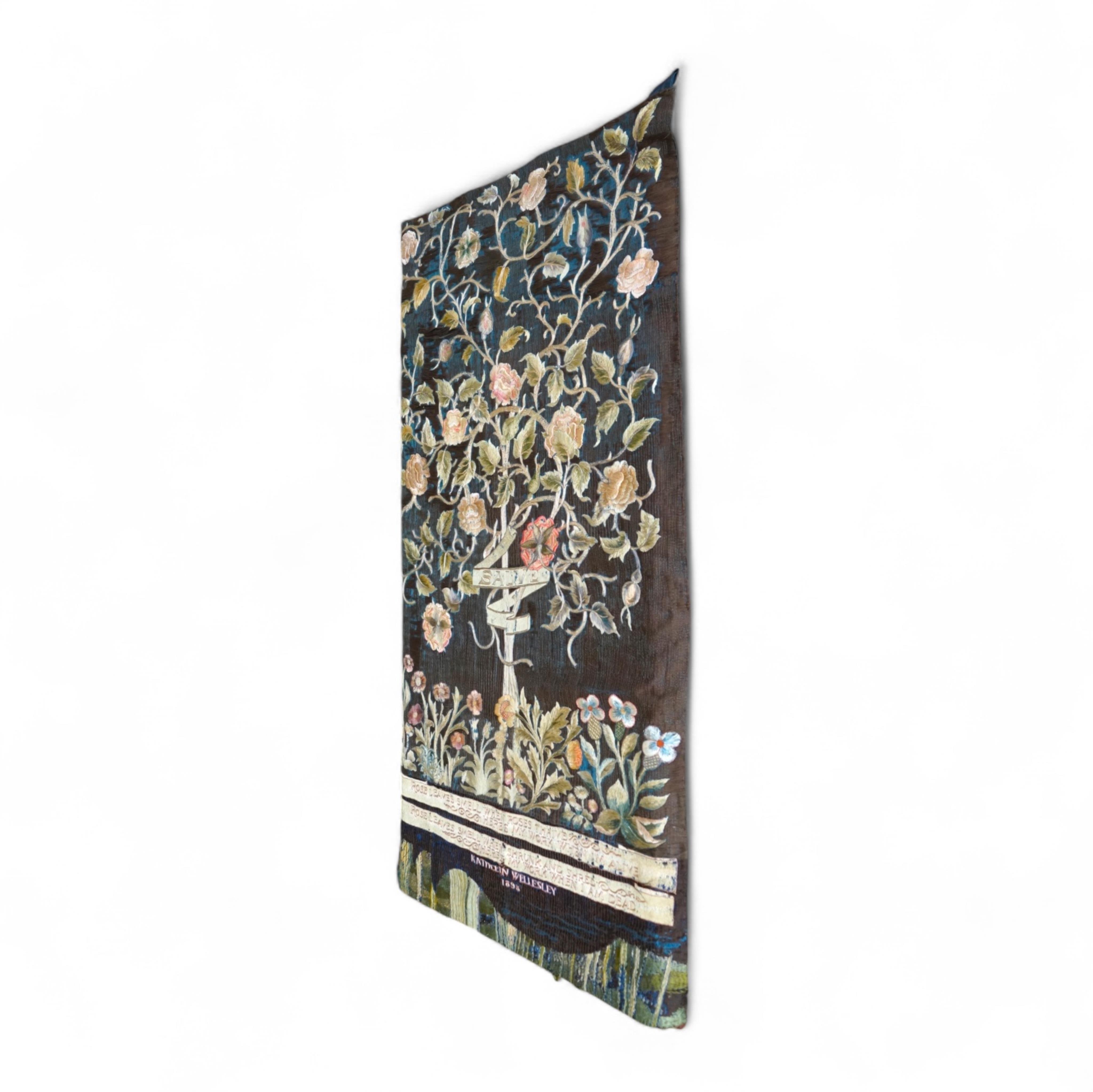 A large Arts and Crafts silk embroidered wall hanging, embroidered in the manner of May Morris with a large central scrolling flowering rose tree and banner embroidered with Salve and a two row motto below;, Rose leaves